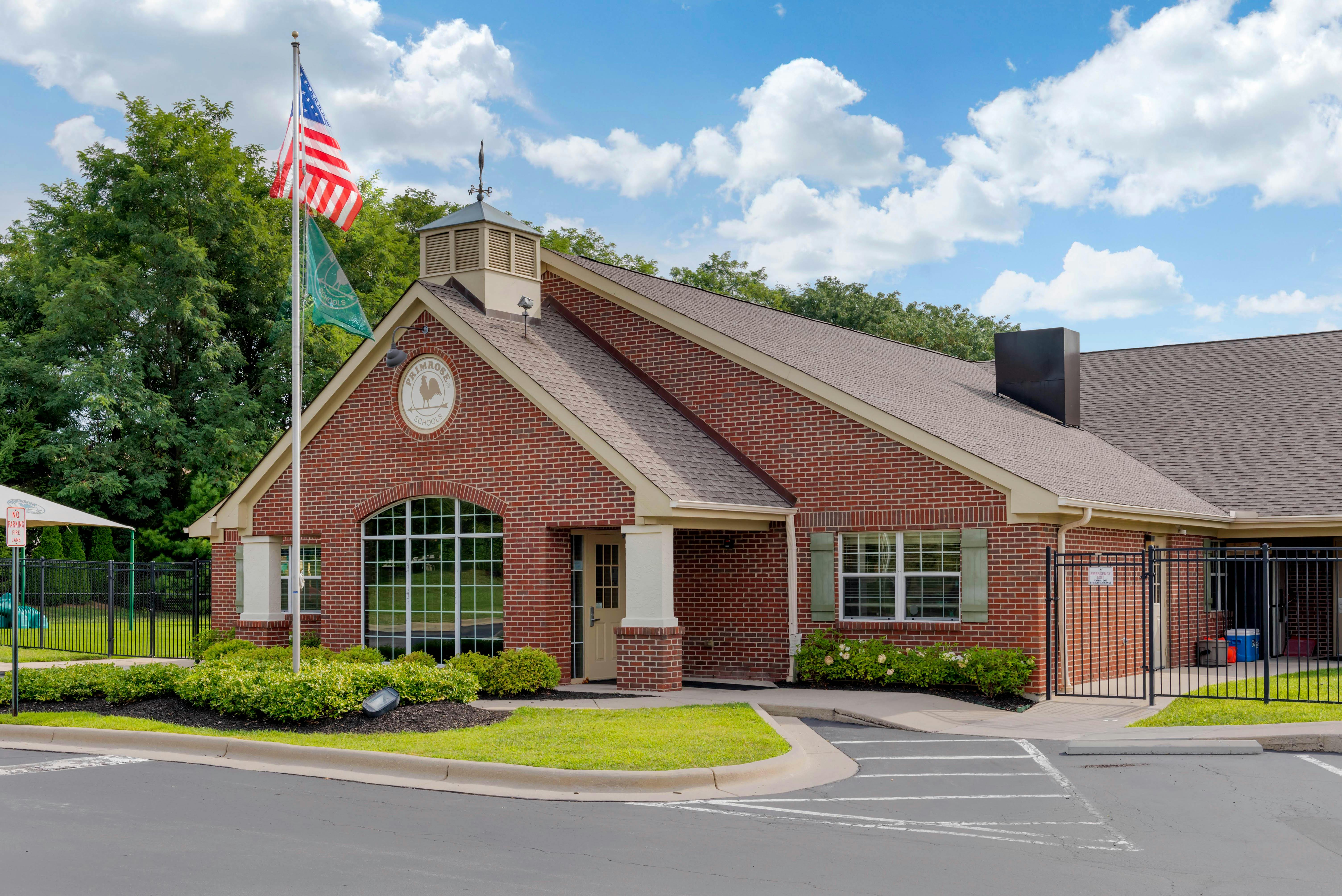 Brick building with a weather vane, US flag, and a green flag, Primrose Schools