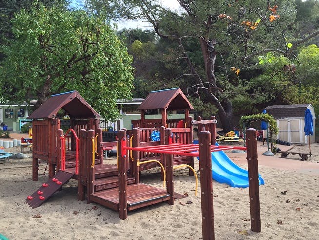 Wooden playground structure with a blue slide on sand