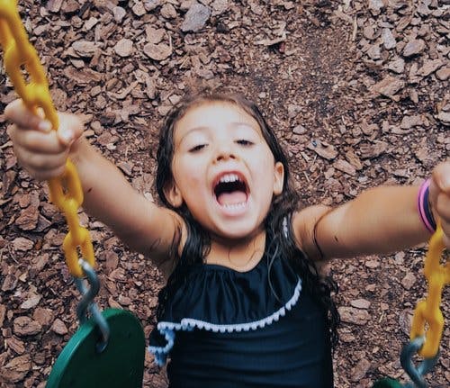 Child on a swing, looking up with mouth open
