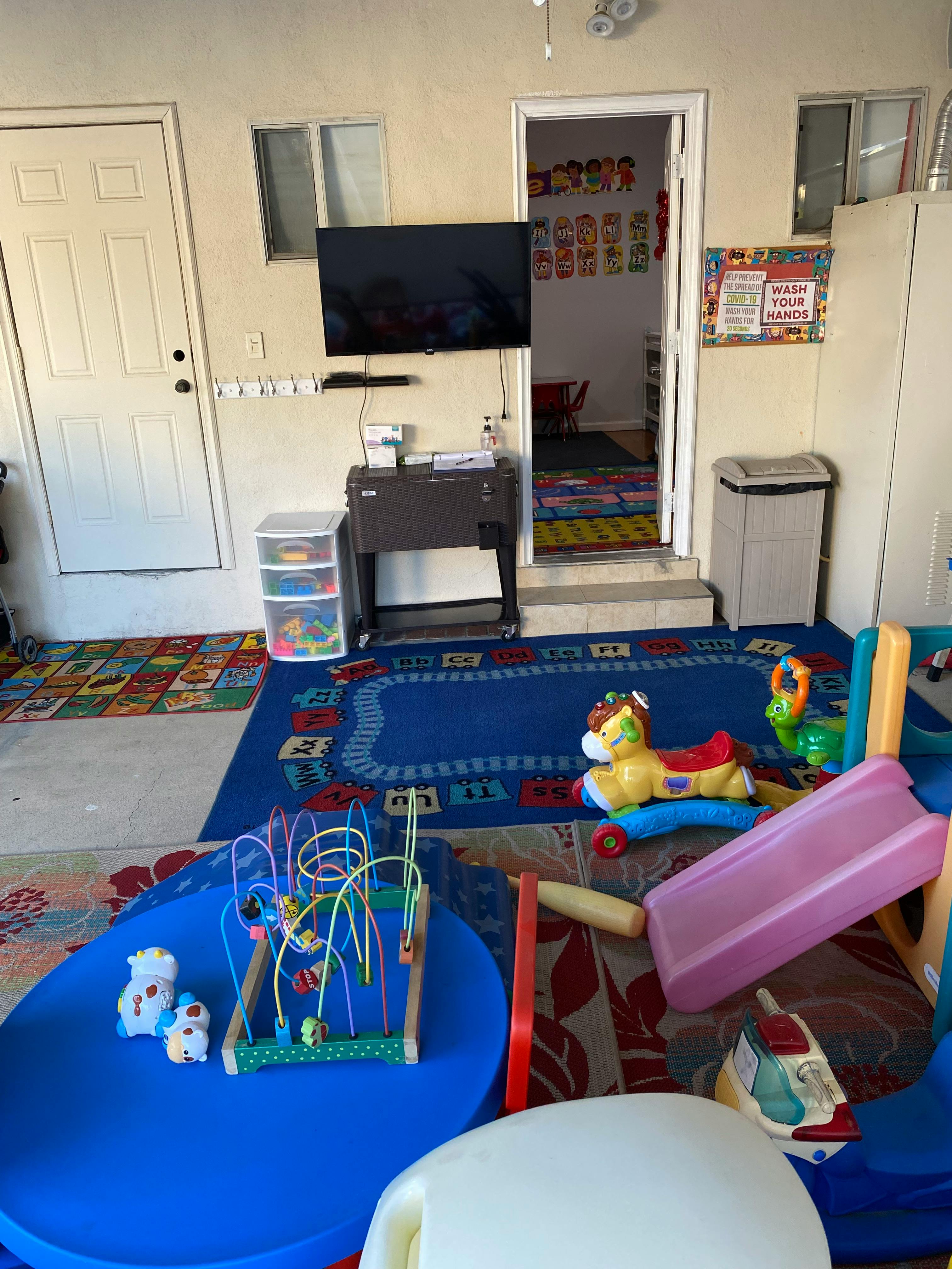 Playroom with colorful rugs, toys, and a small slide