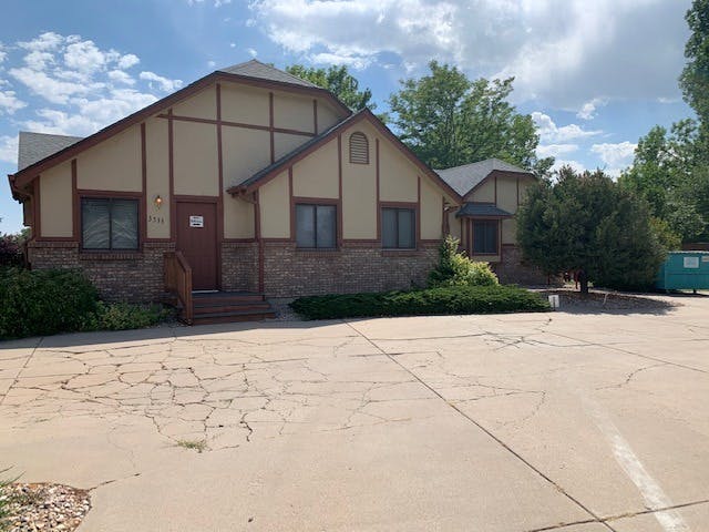 Building with tan siding, brown trim, and stone facade