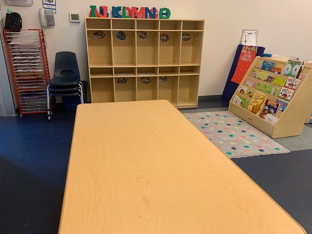 Classroom with a table, storage cubbies, and a book display