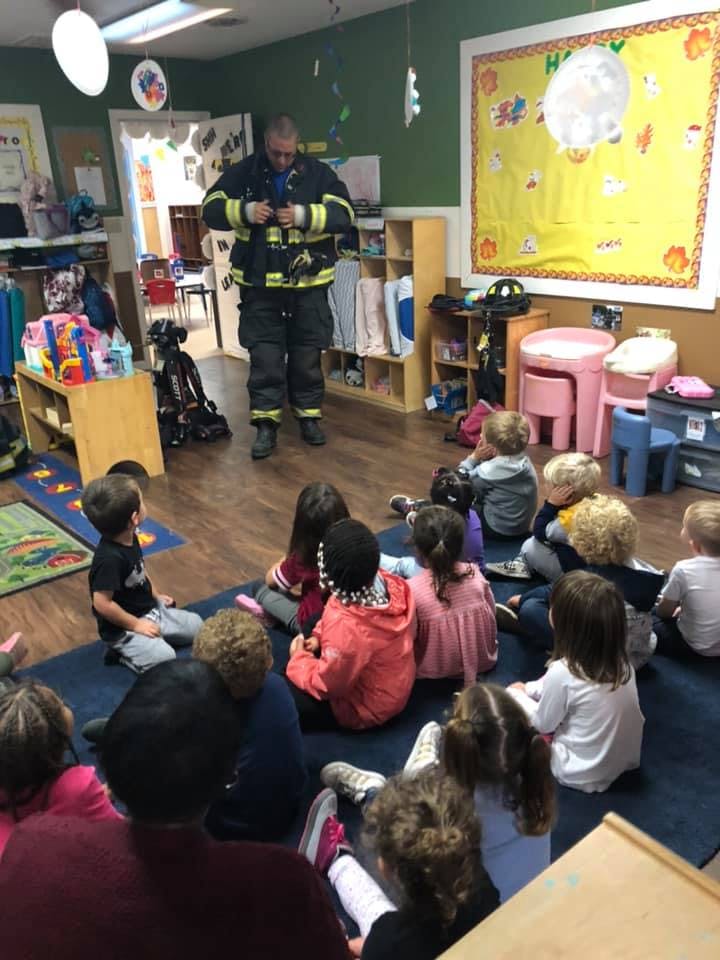 Firefighter in uniform standing in front of children sitting on the floor