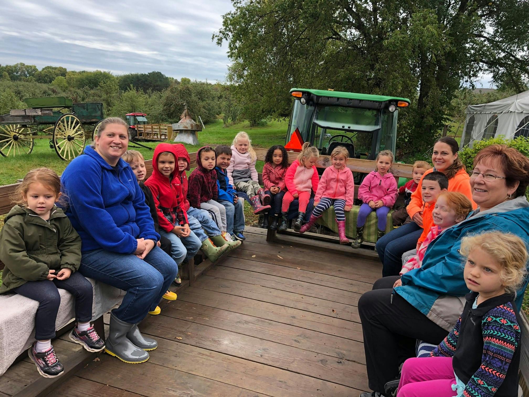 People and children sitting on a wooden trailer