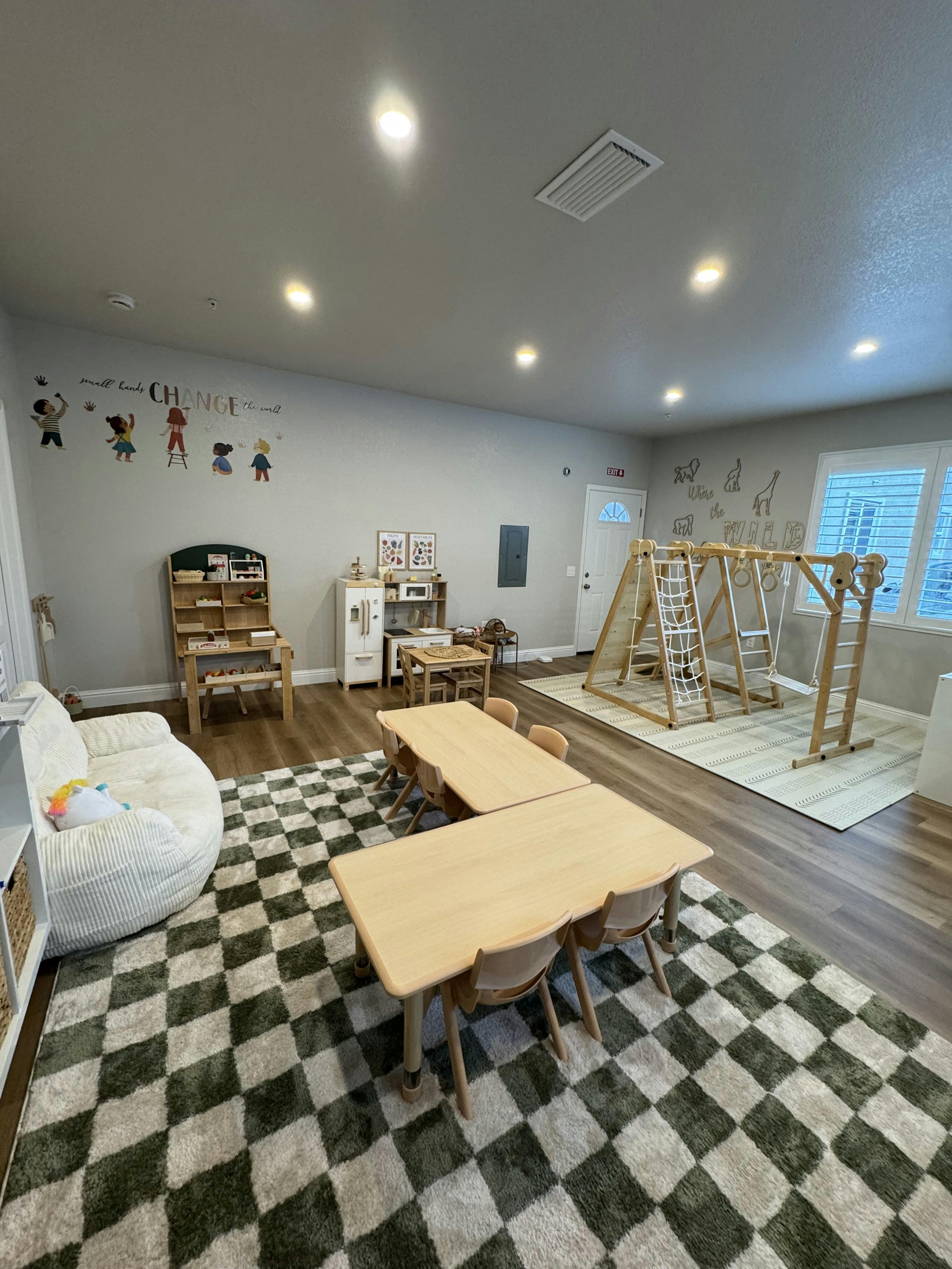 Playroom with small tables and chairs, a climbing structure, and a checkered rug