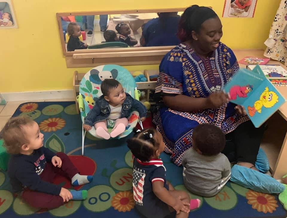 Person reading a book to several children in a classroom