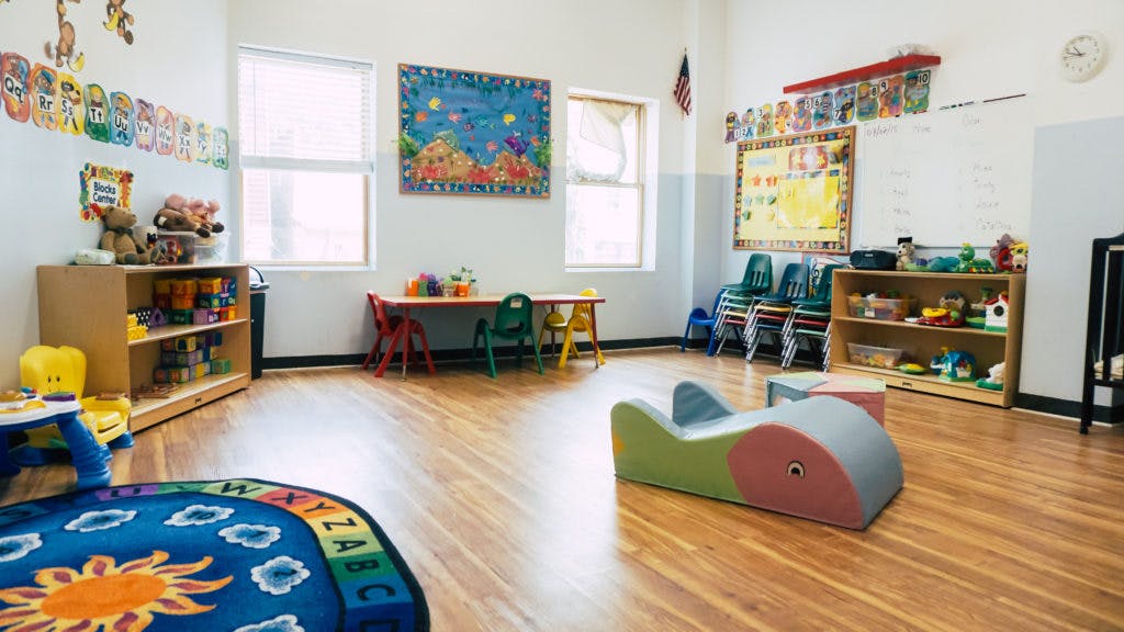 Empty classroom with small tables, chairs, and toys