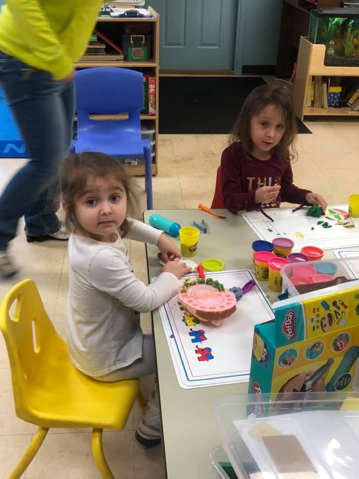 Two children playing with modeling clay at a table