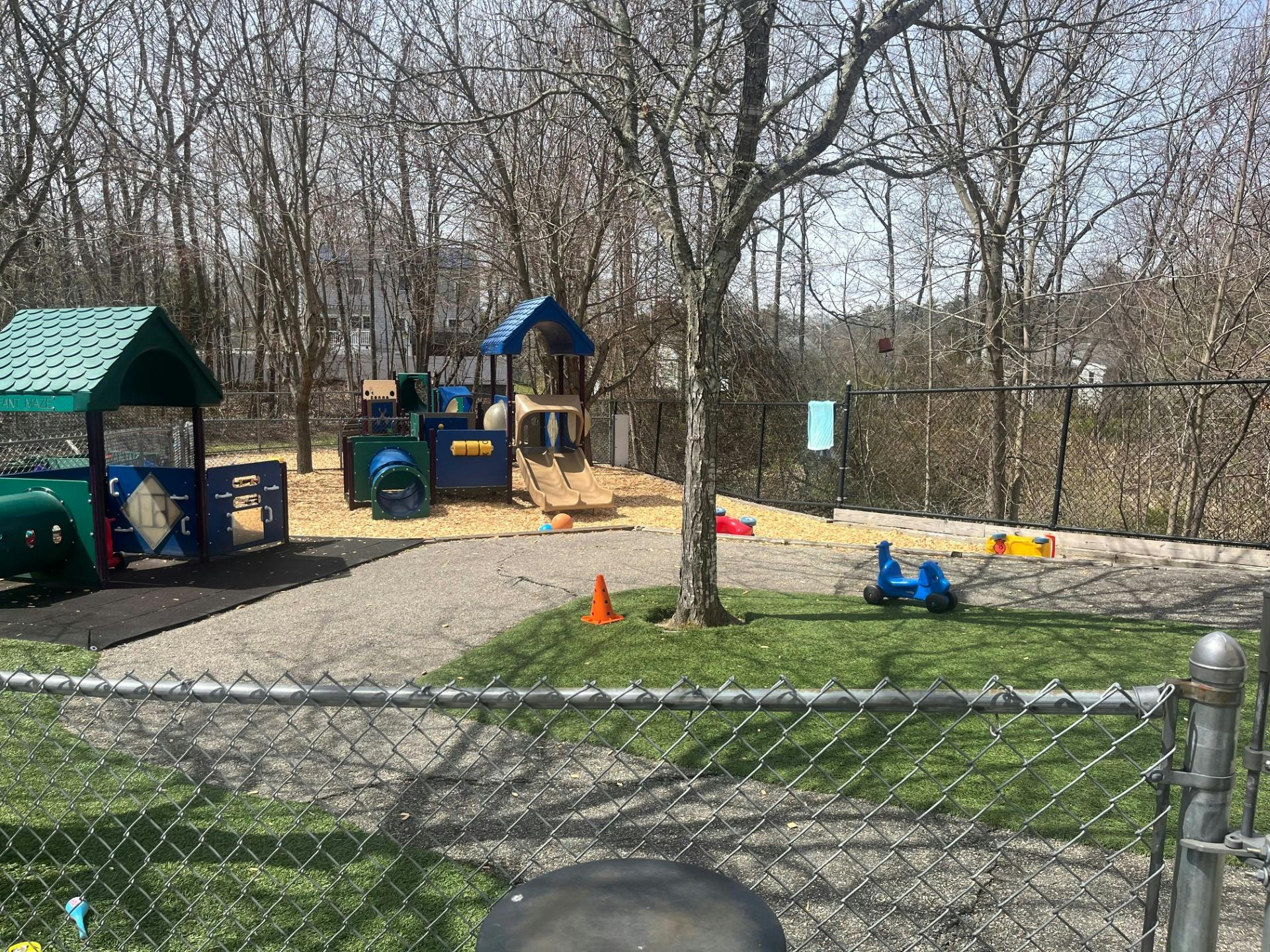 An outdoor playground with colorful equipment, slides, and ride-on toys