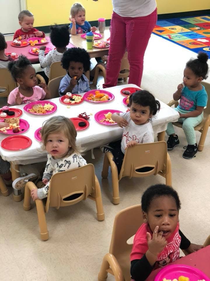 Children sitting at tables with plates of food