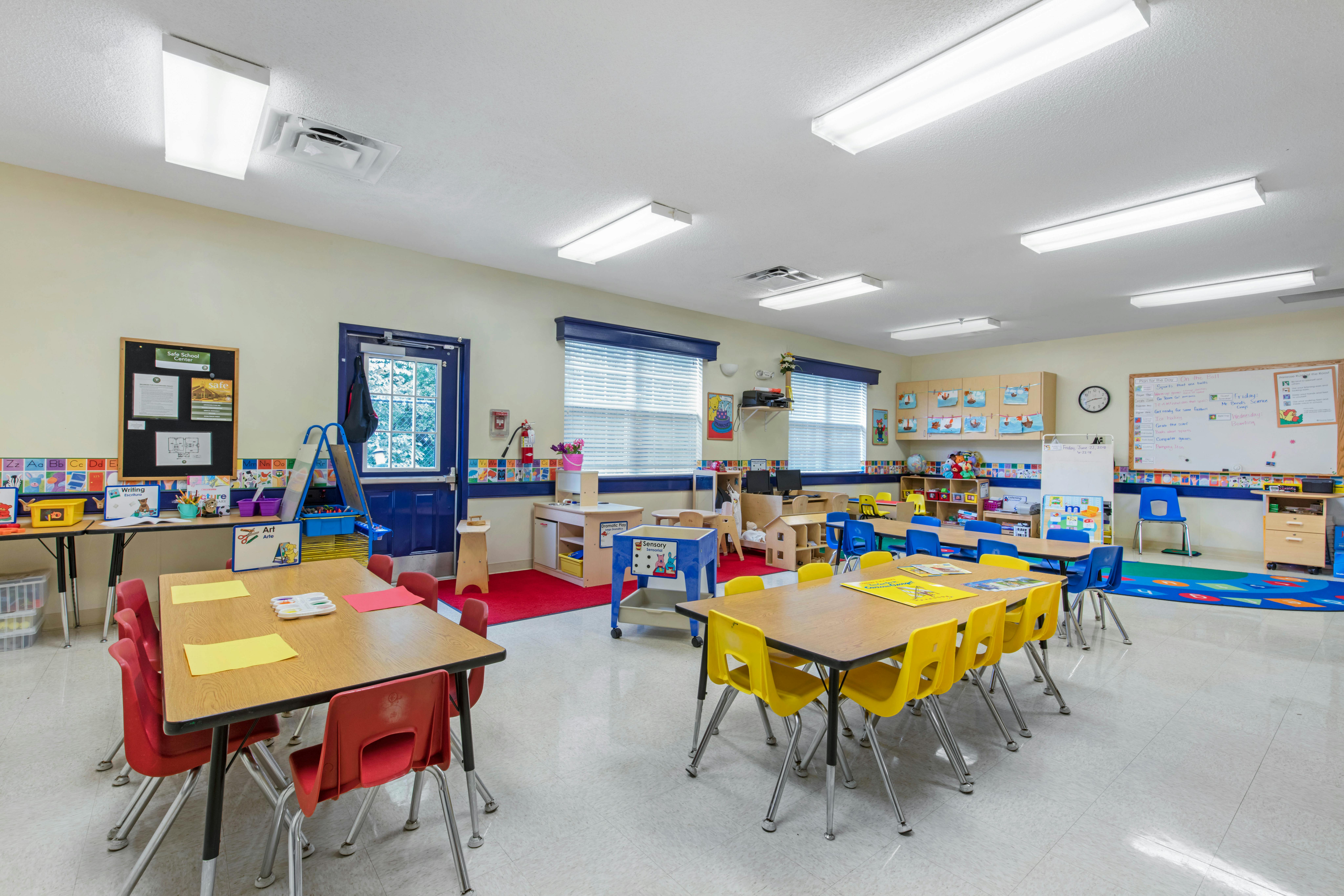 Empty colorful preschool classroom with small tables and chairs