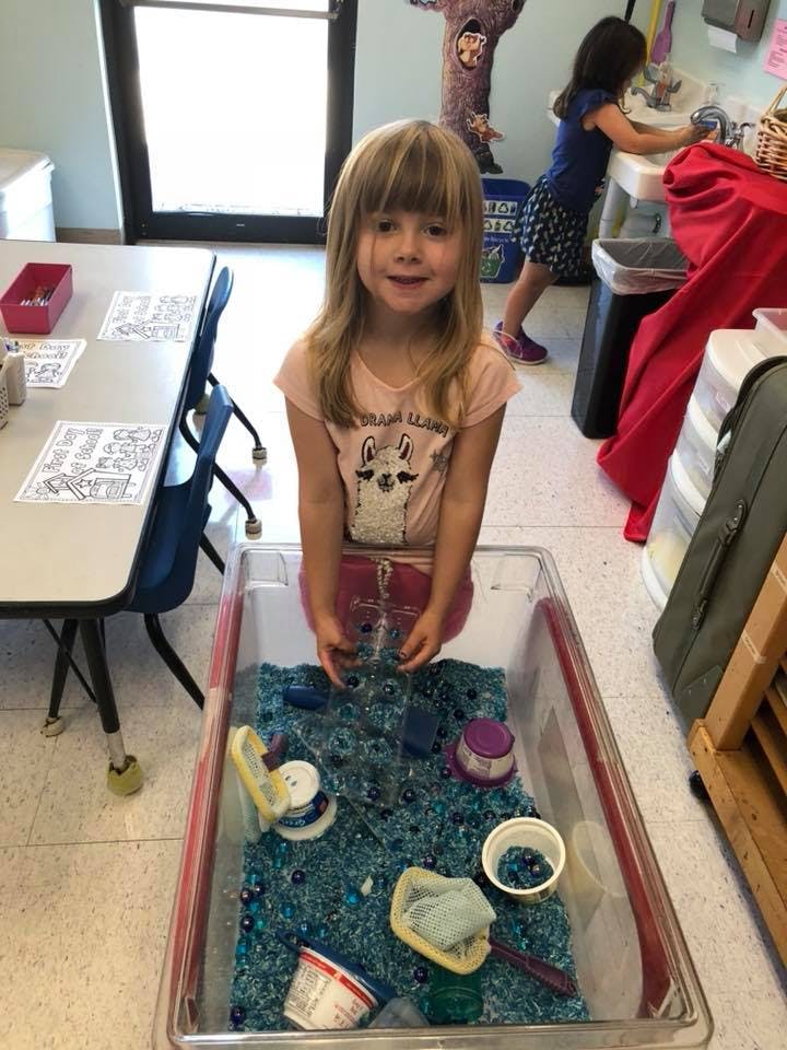 Child playing with sensory bin in a classroom