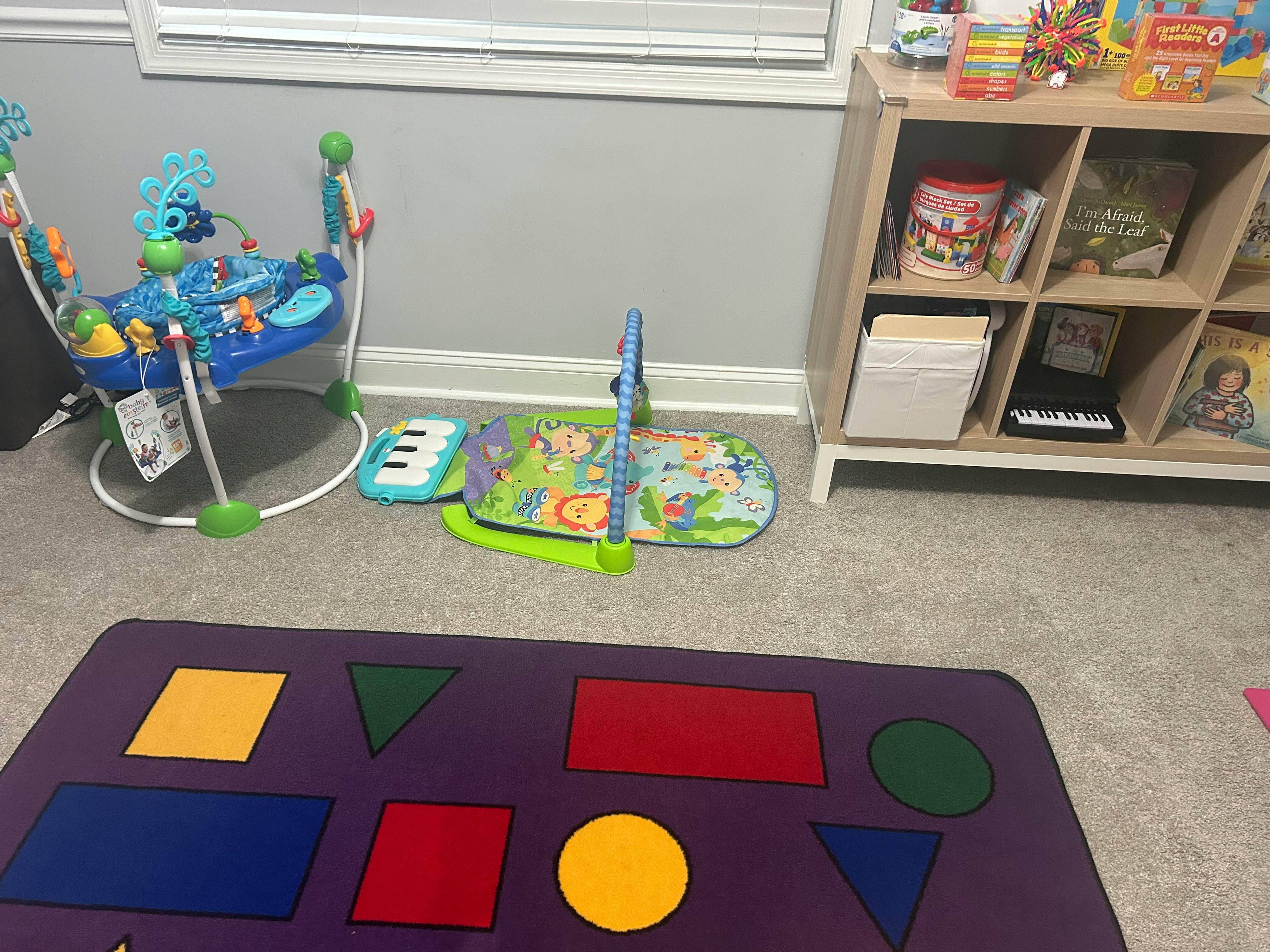 Baby bouncer, play mat, and shape rug in a room