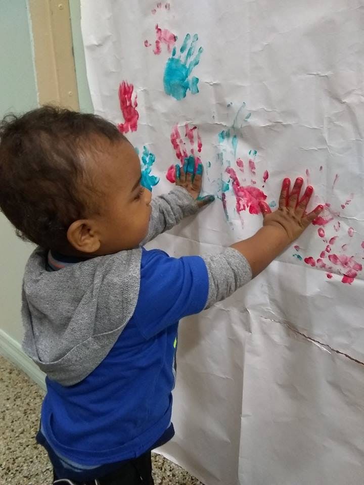 Child making handprints on paper