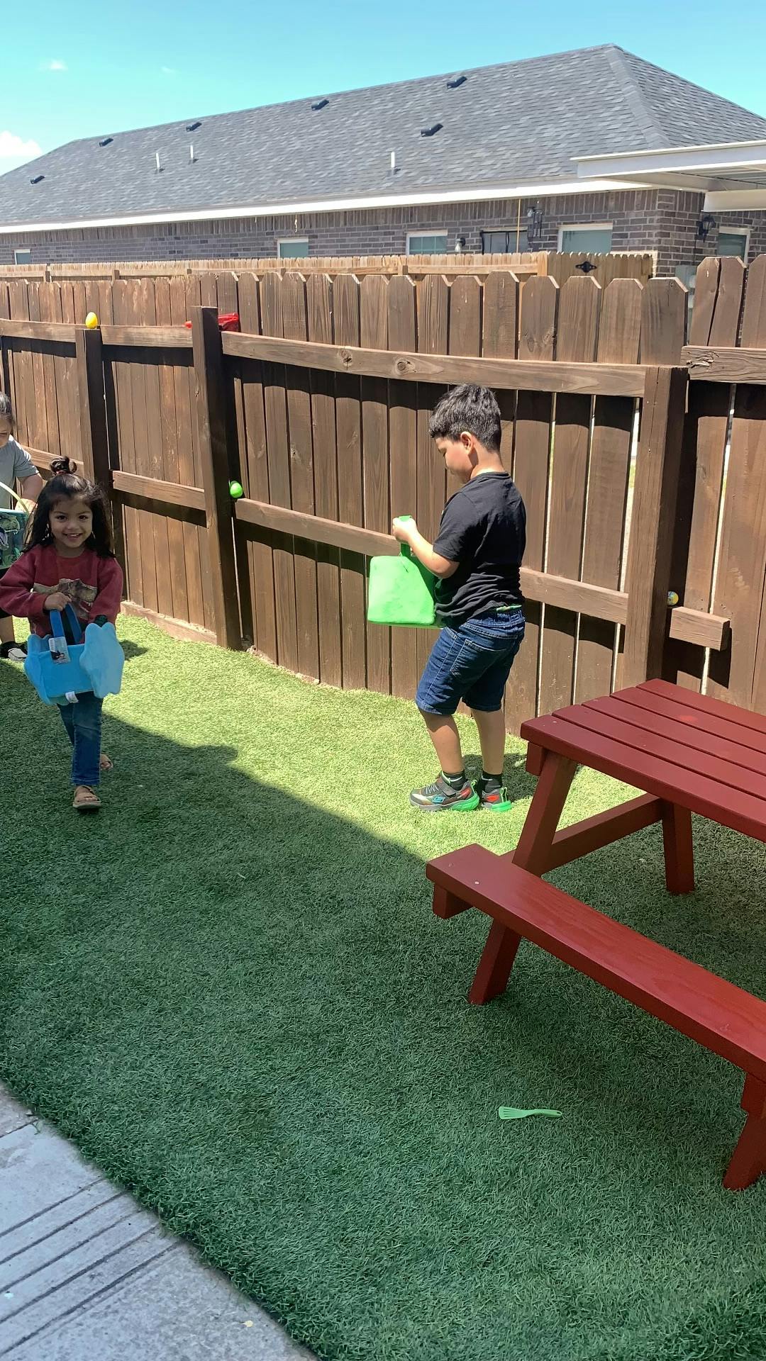 Two children holding bags in a grassy yard