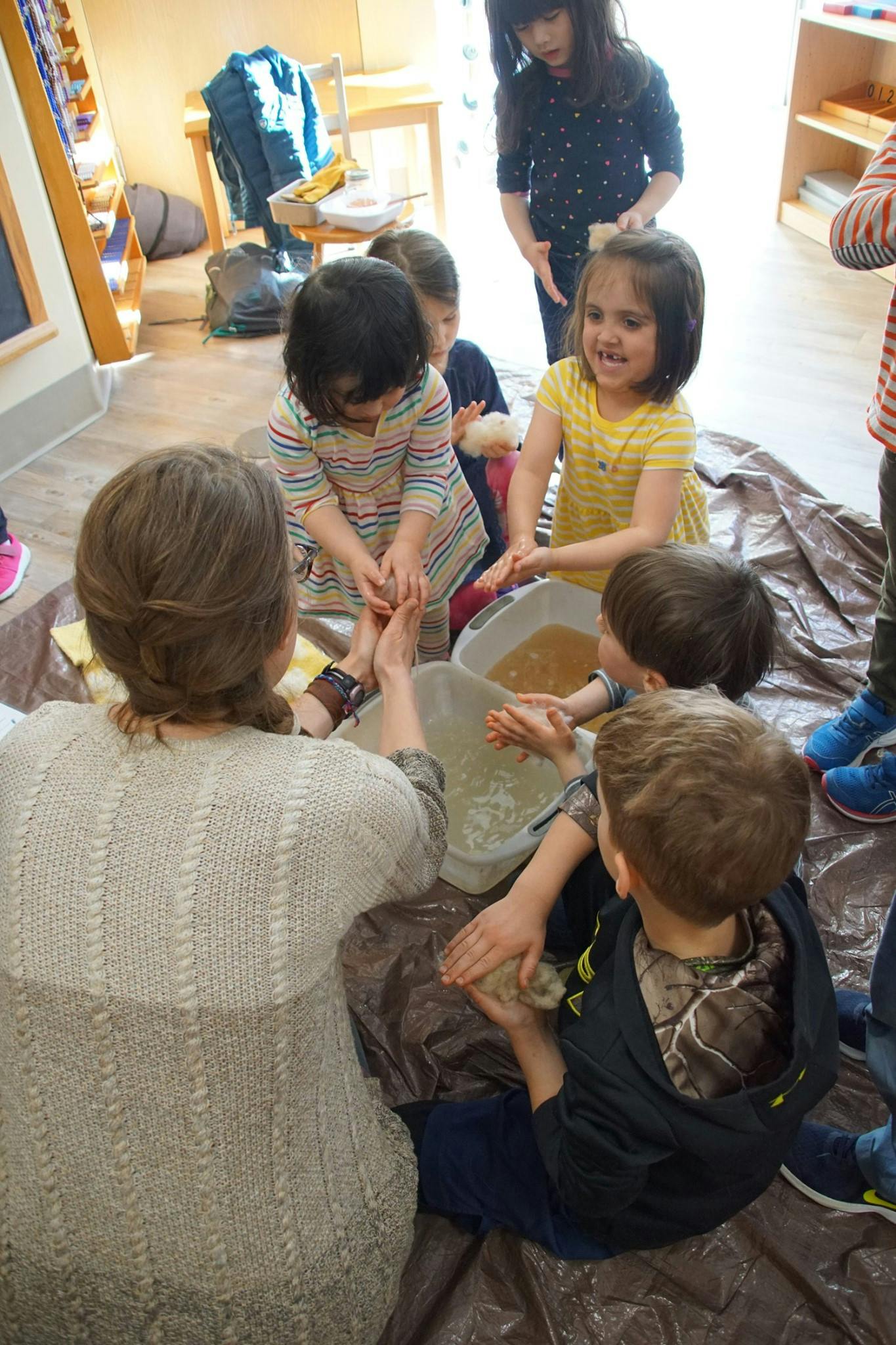 Adult and children washing feet in a classroom
