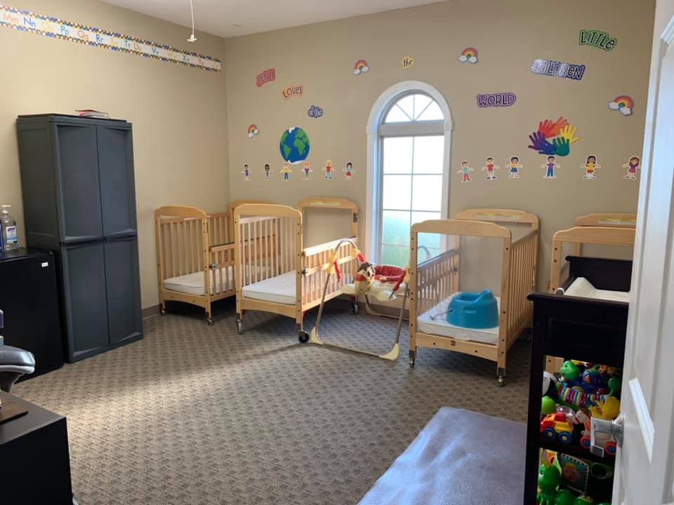 Room with multiple cribs and a window