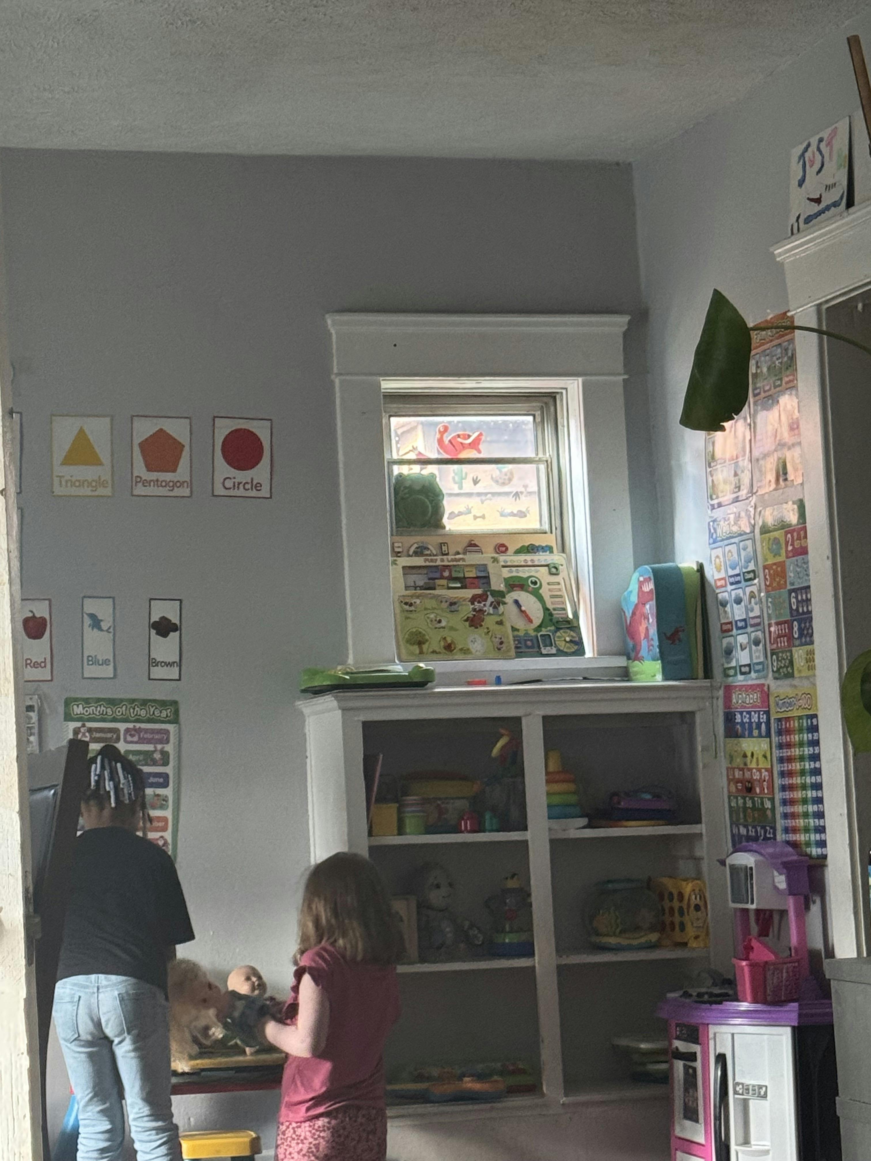 Two children playing in a room with educational wall charts and a toy shelf