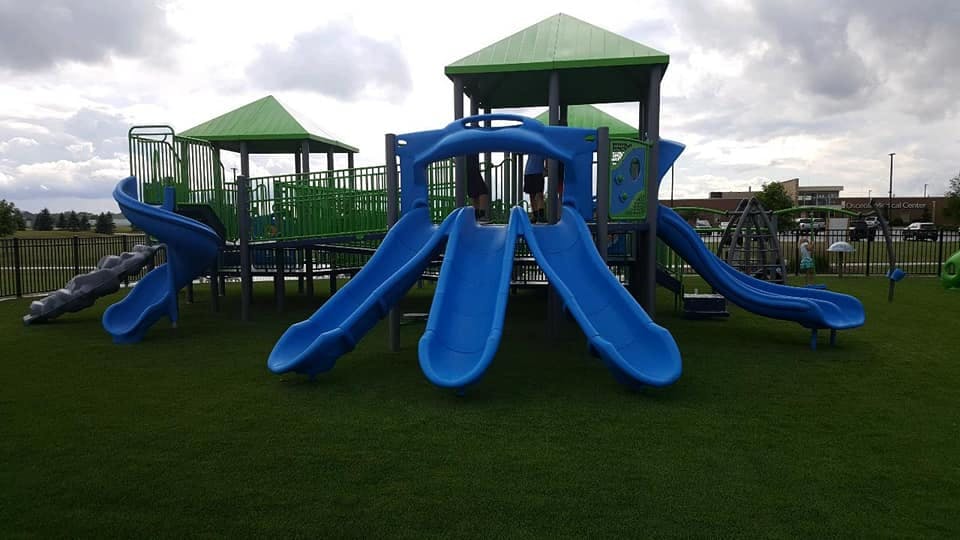 Playground with blue slides and green roofs on artificial turf