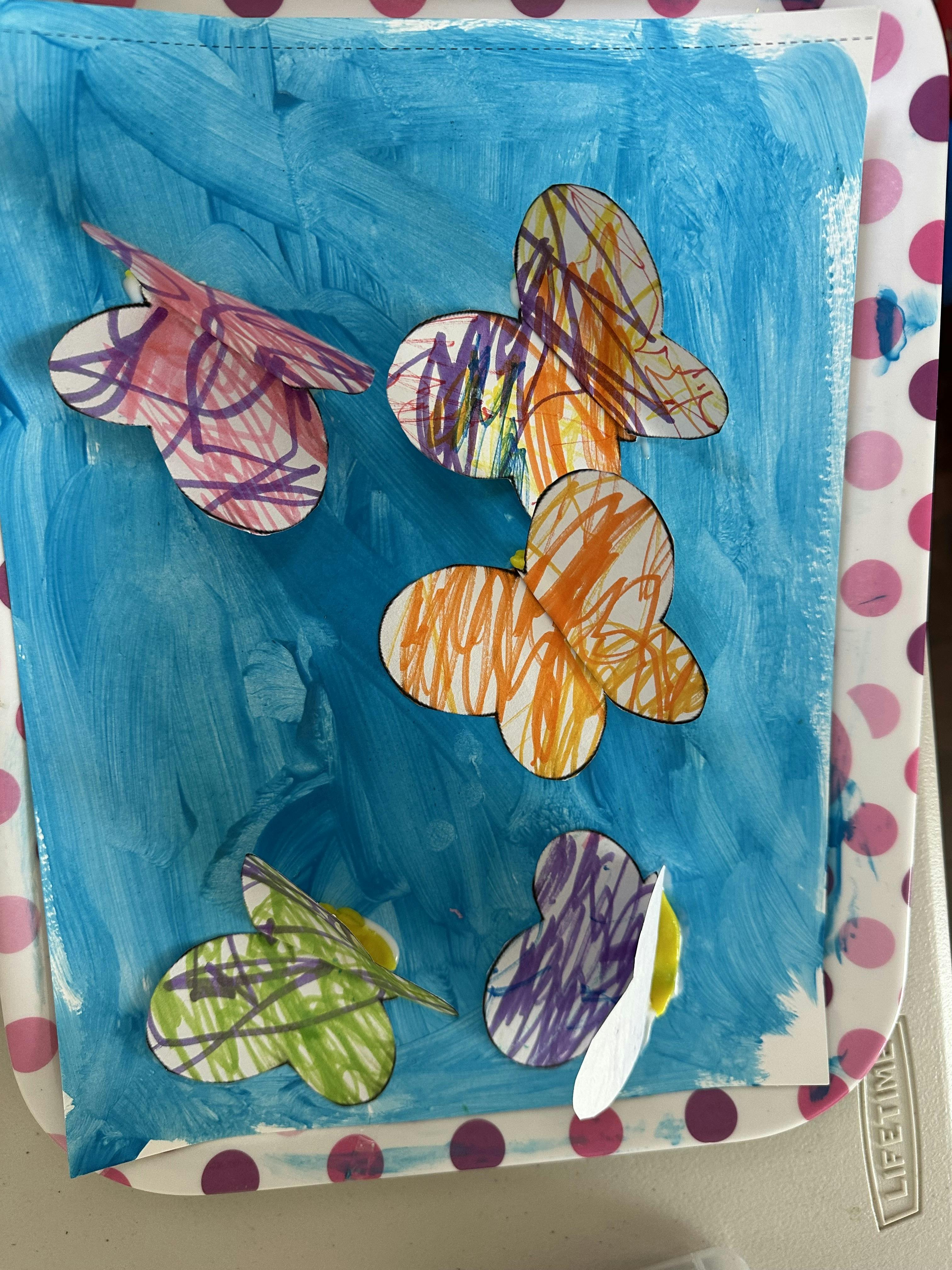 Child's craft project with painted blue background and colorful paper butterflies