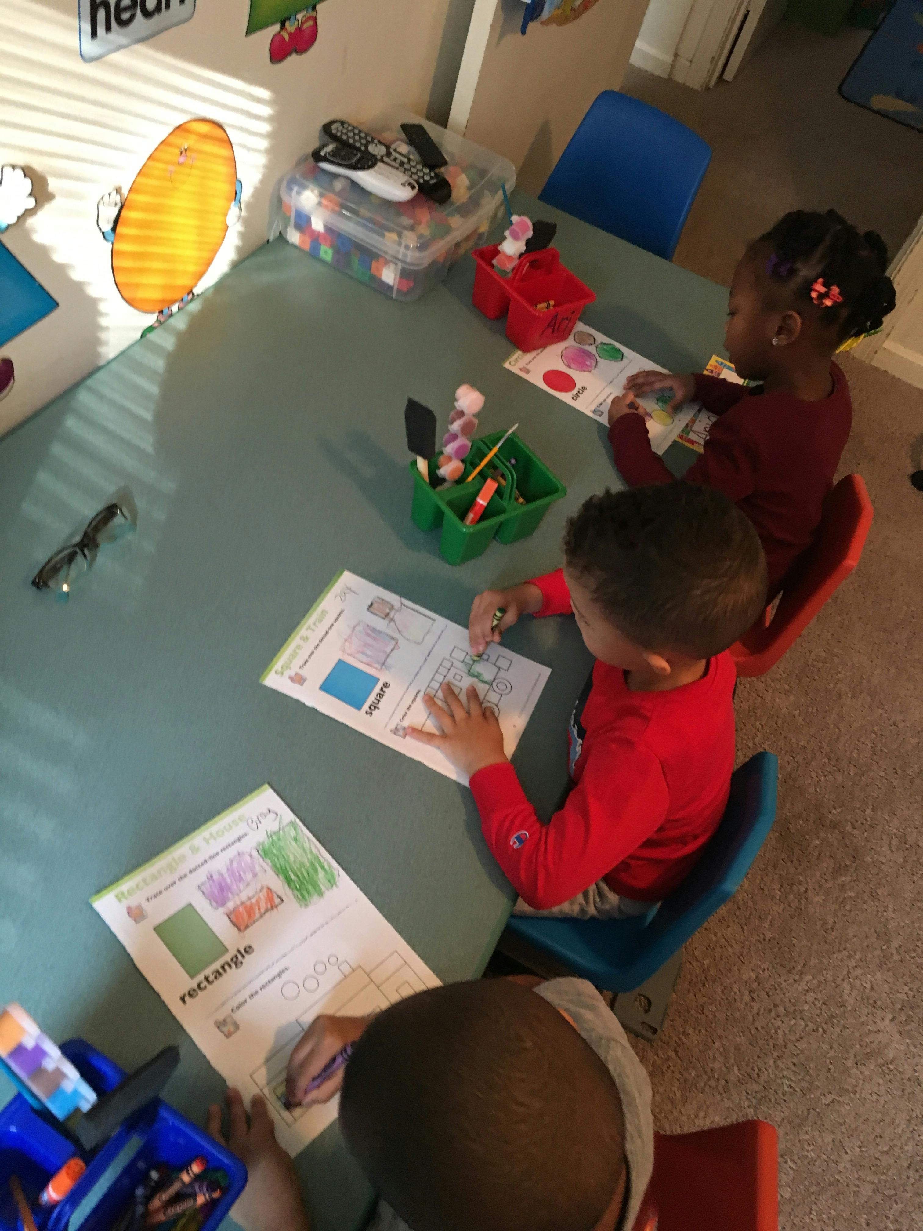 Three children sitting at a table doing schoolwork