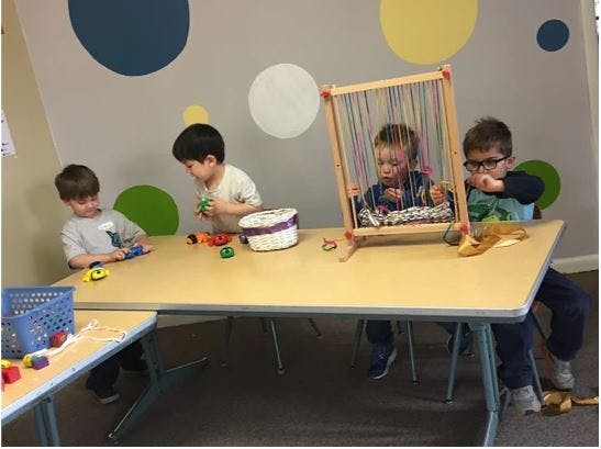 Children playing with toys at a table in a classroom