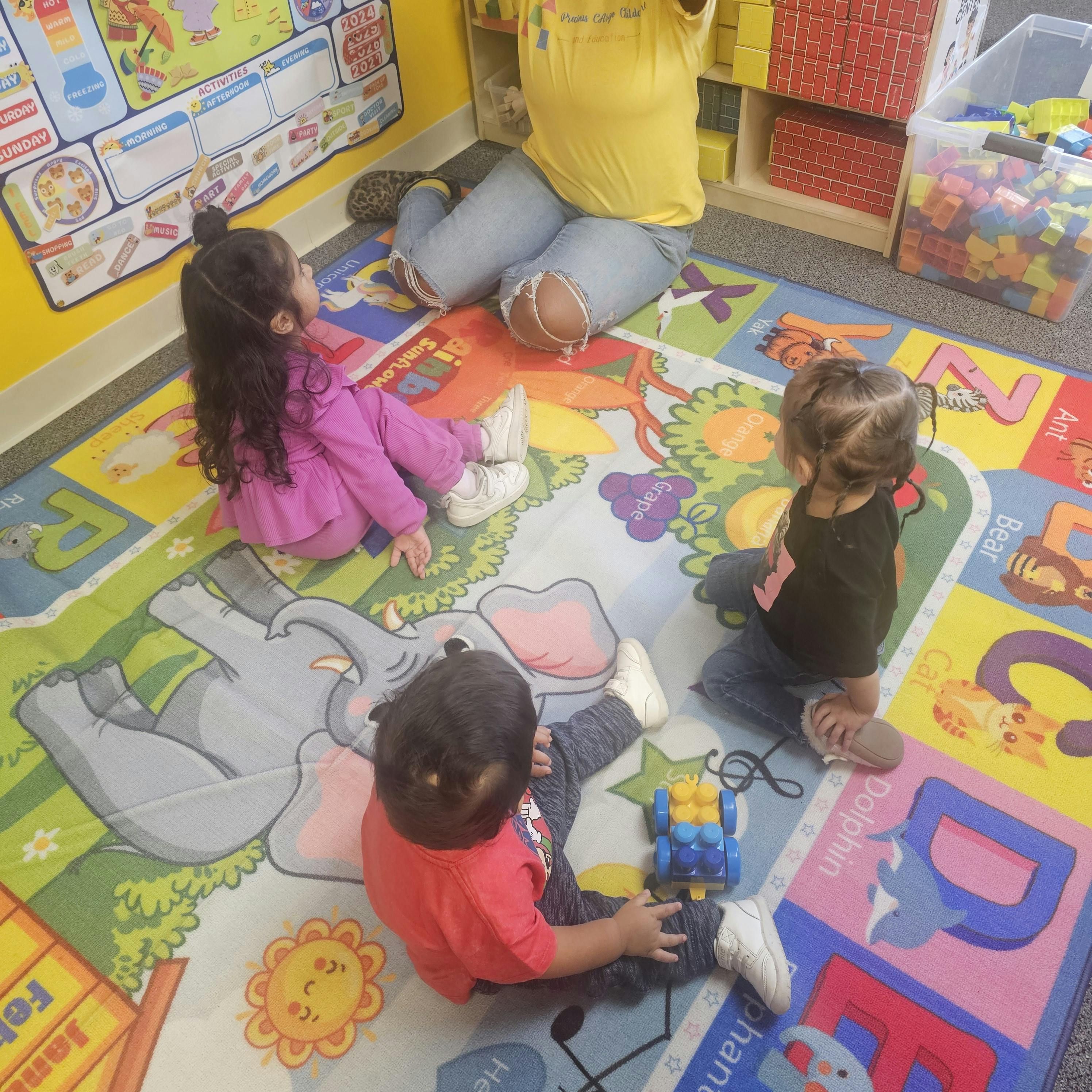 Children sitting on a colorful alphabet rug