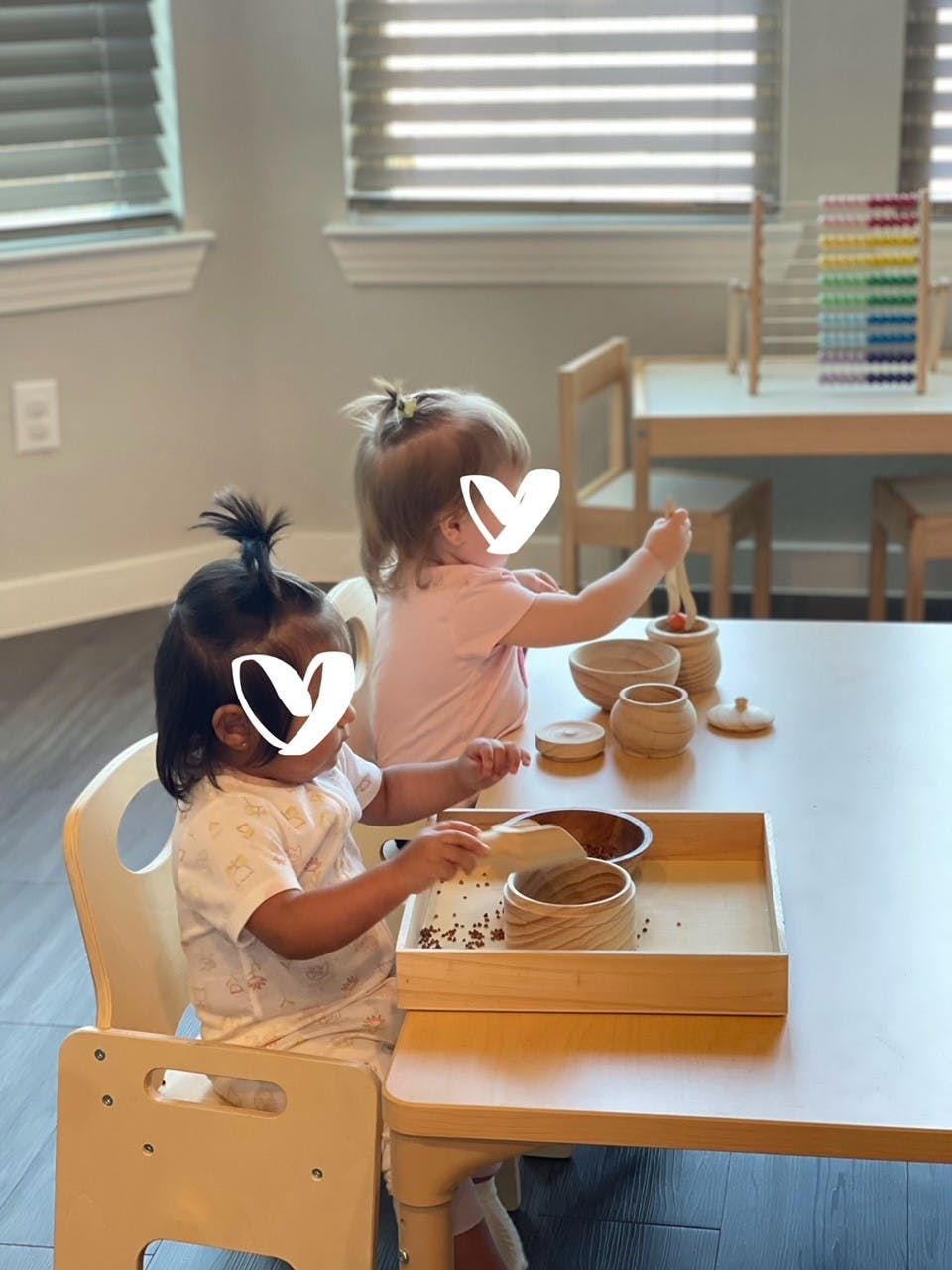 Two children playing with wooden bowls and scoops at a table