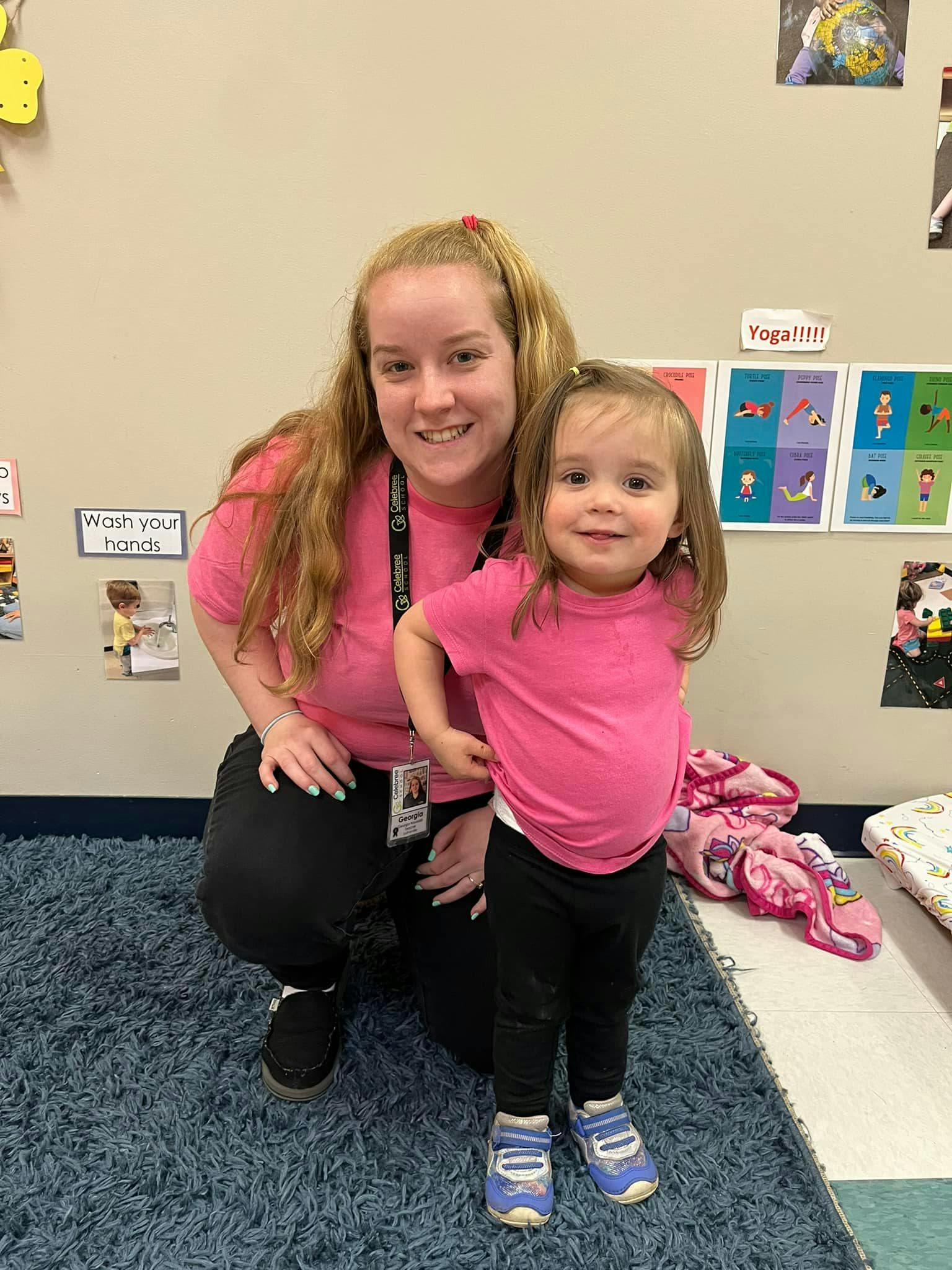 Person kneeling next to a child, both smiling