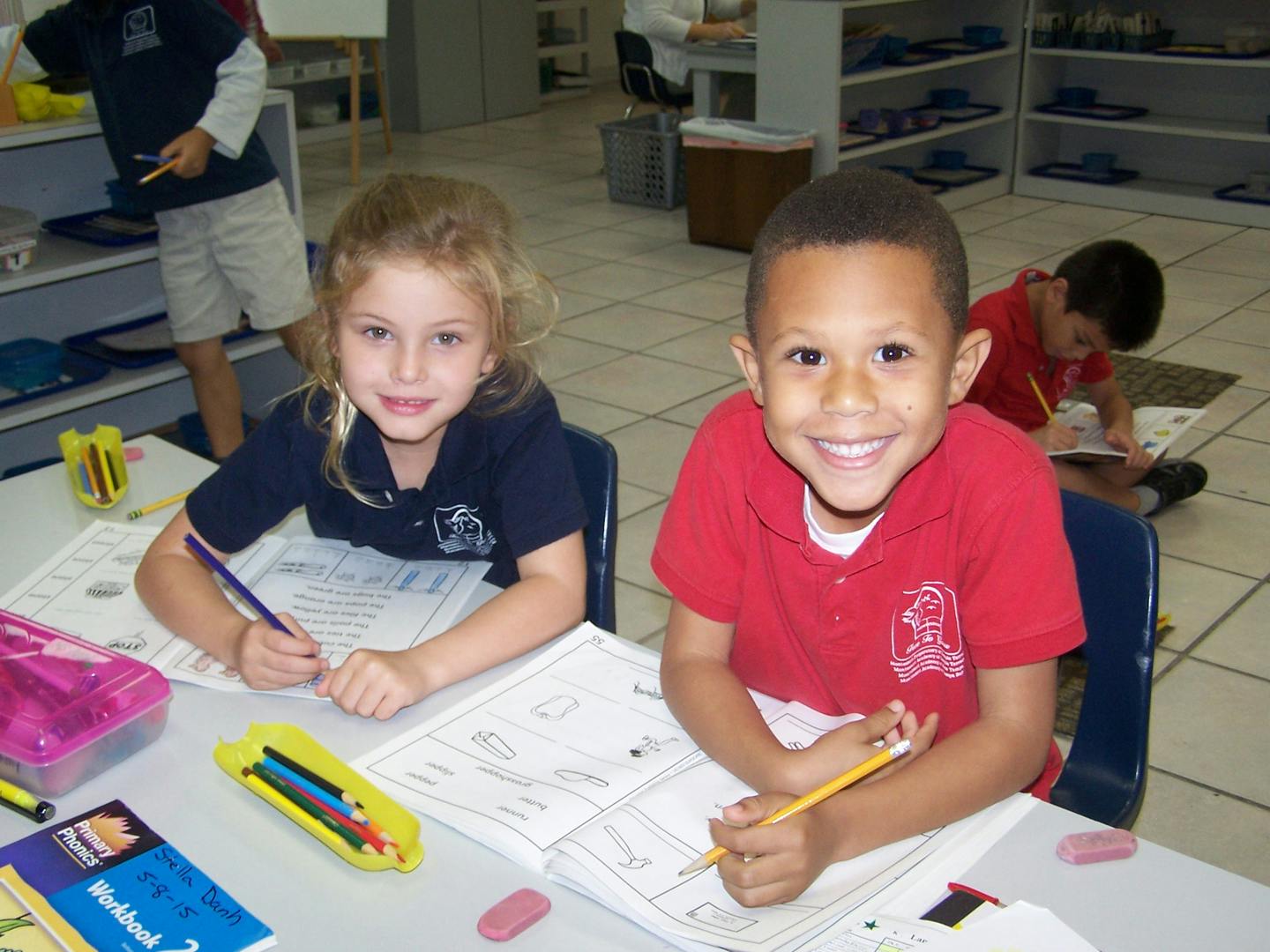 Two children sitting at a desk with pencils and papers