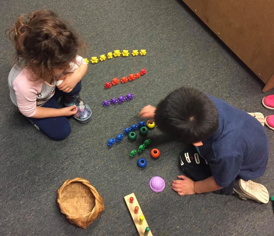 Two children playing with colorful linking toys on a carpeted floor