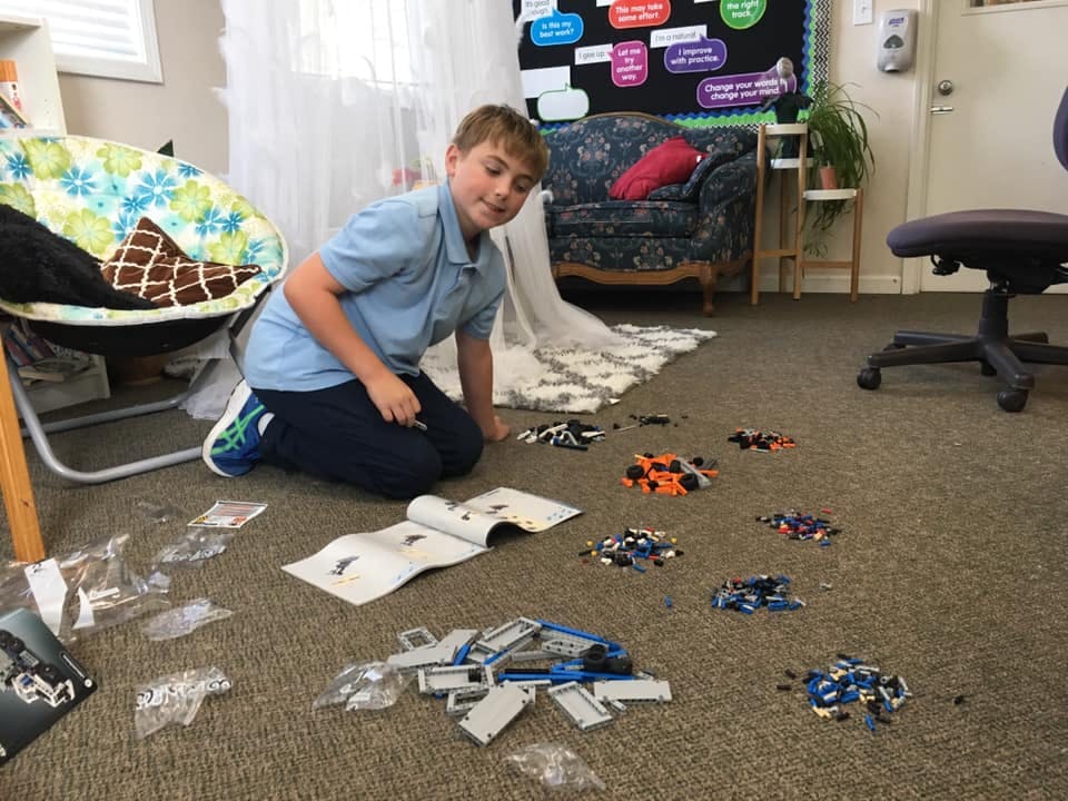 Child kneeling on floor with building blocks and instructions