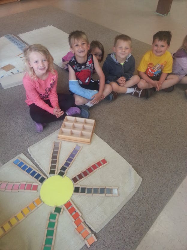 Children sitting on the floor with a color matching activity