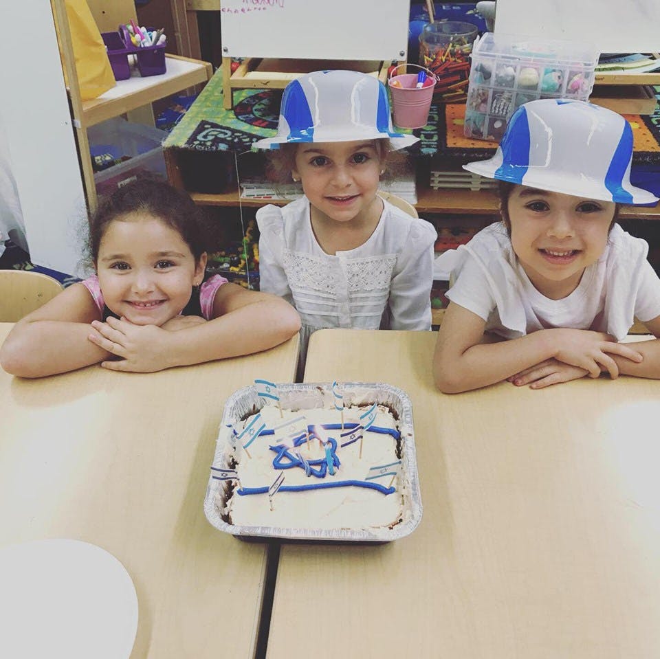 Three children at a table with a cake decorated with blue and white