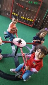 Three children playing on a playground seesaw