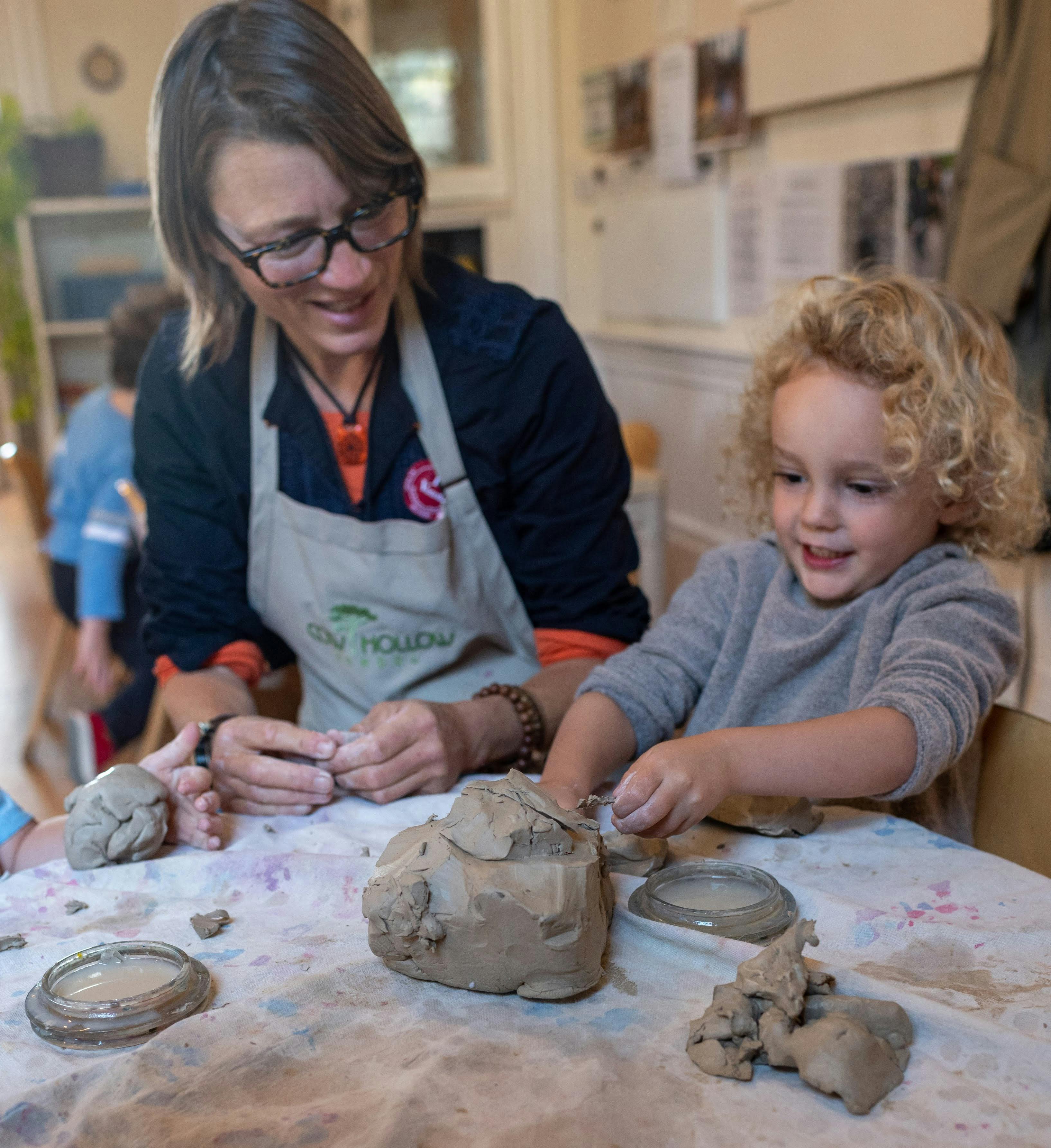 Person and child working with clay at a table
