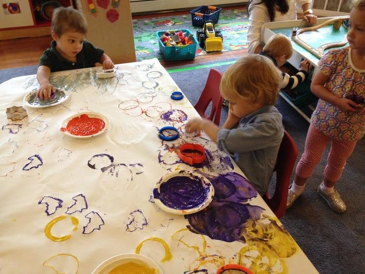 Children finger painting on a large sheet of paper in a classroom