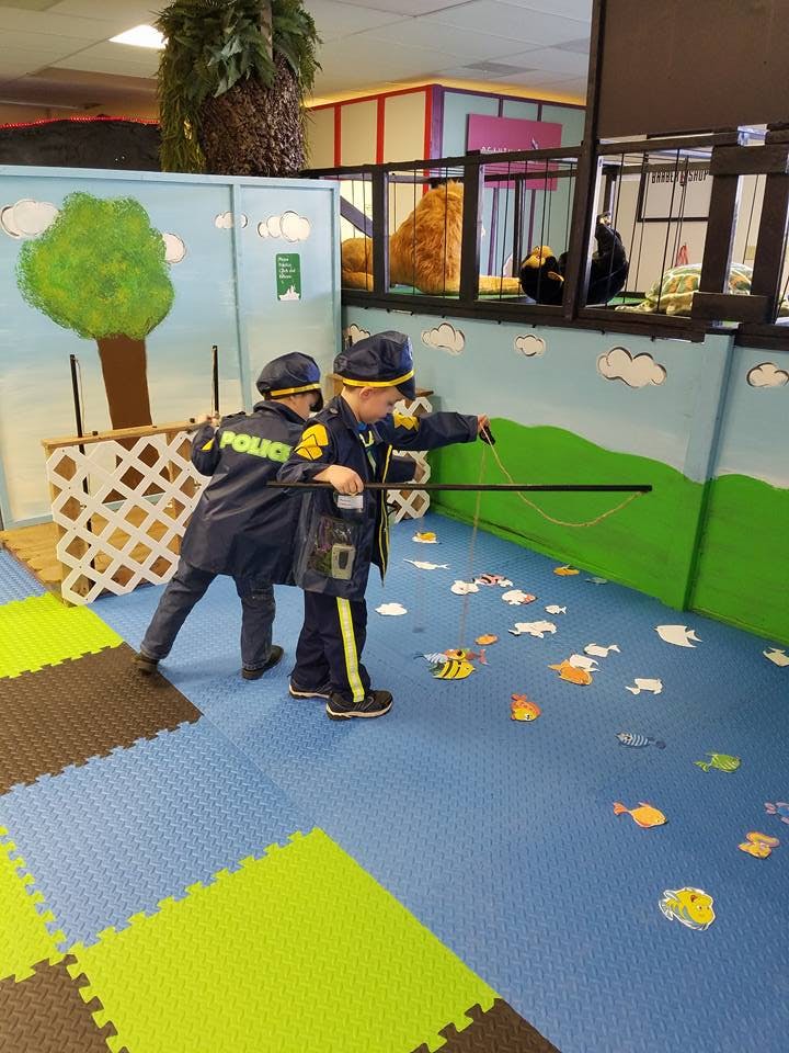 Two children in police costumes playing with a fishing rod