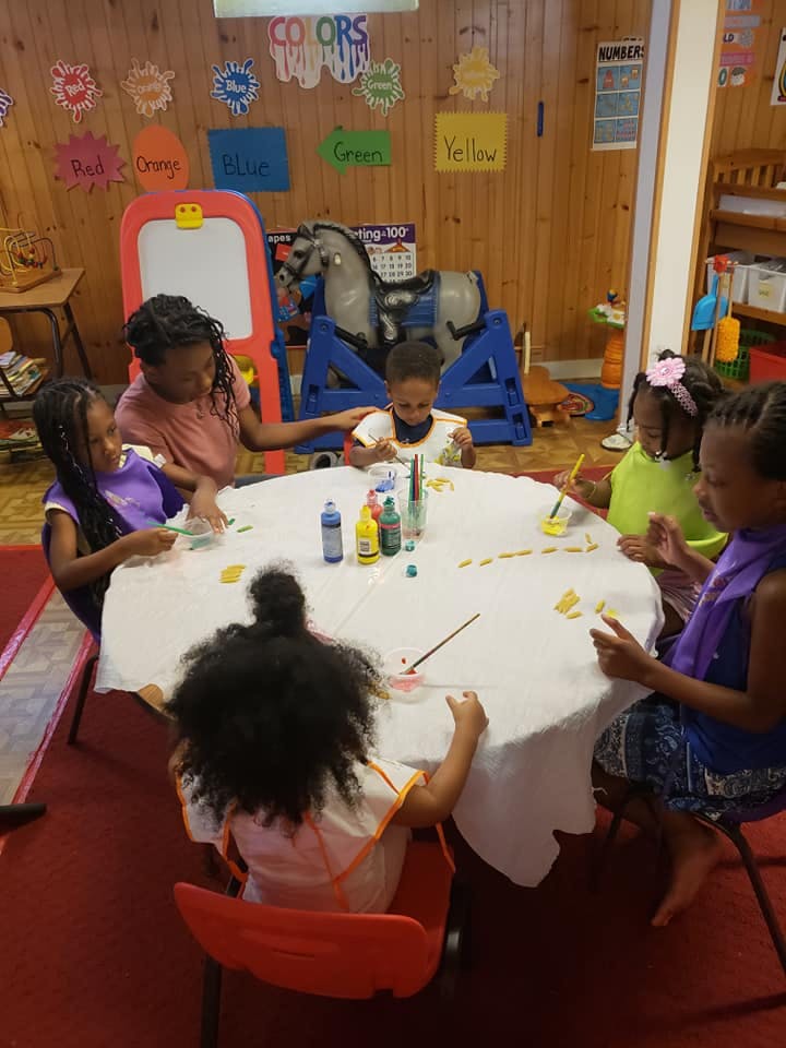 Children painting at a table in a classroom