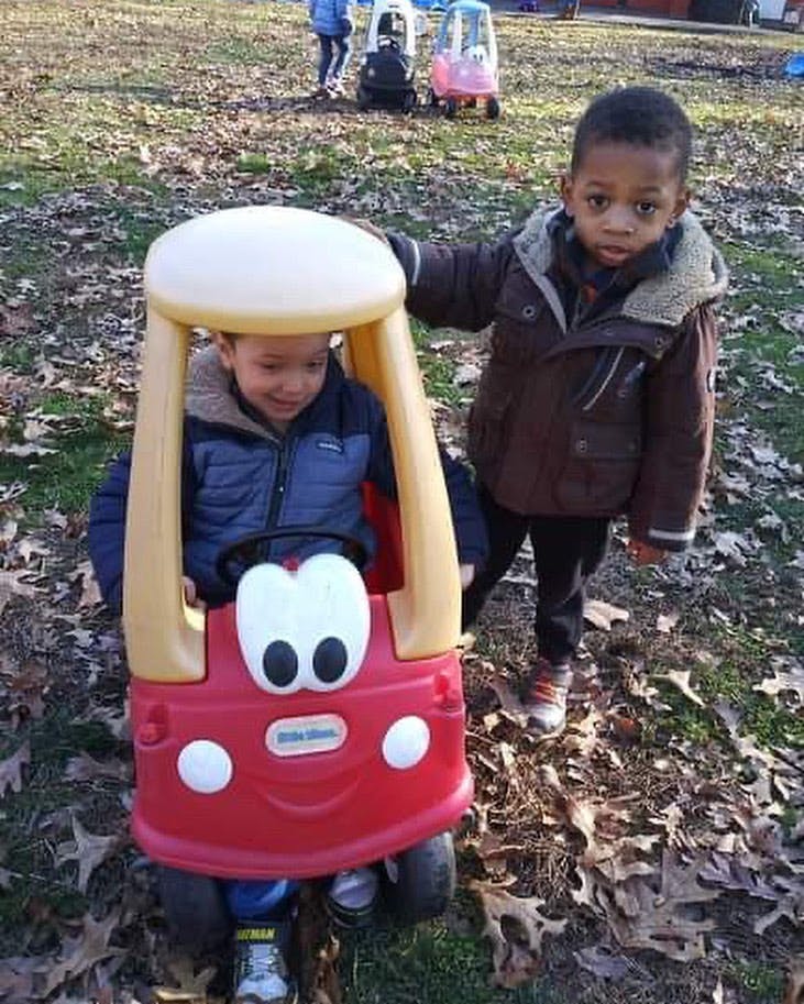 Two children playing with a toy car outdoors