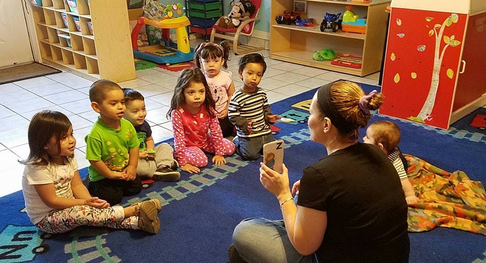 Person holding phone in front of children in a classroom
