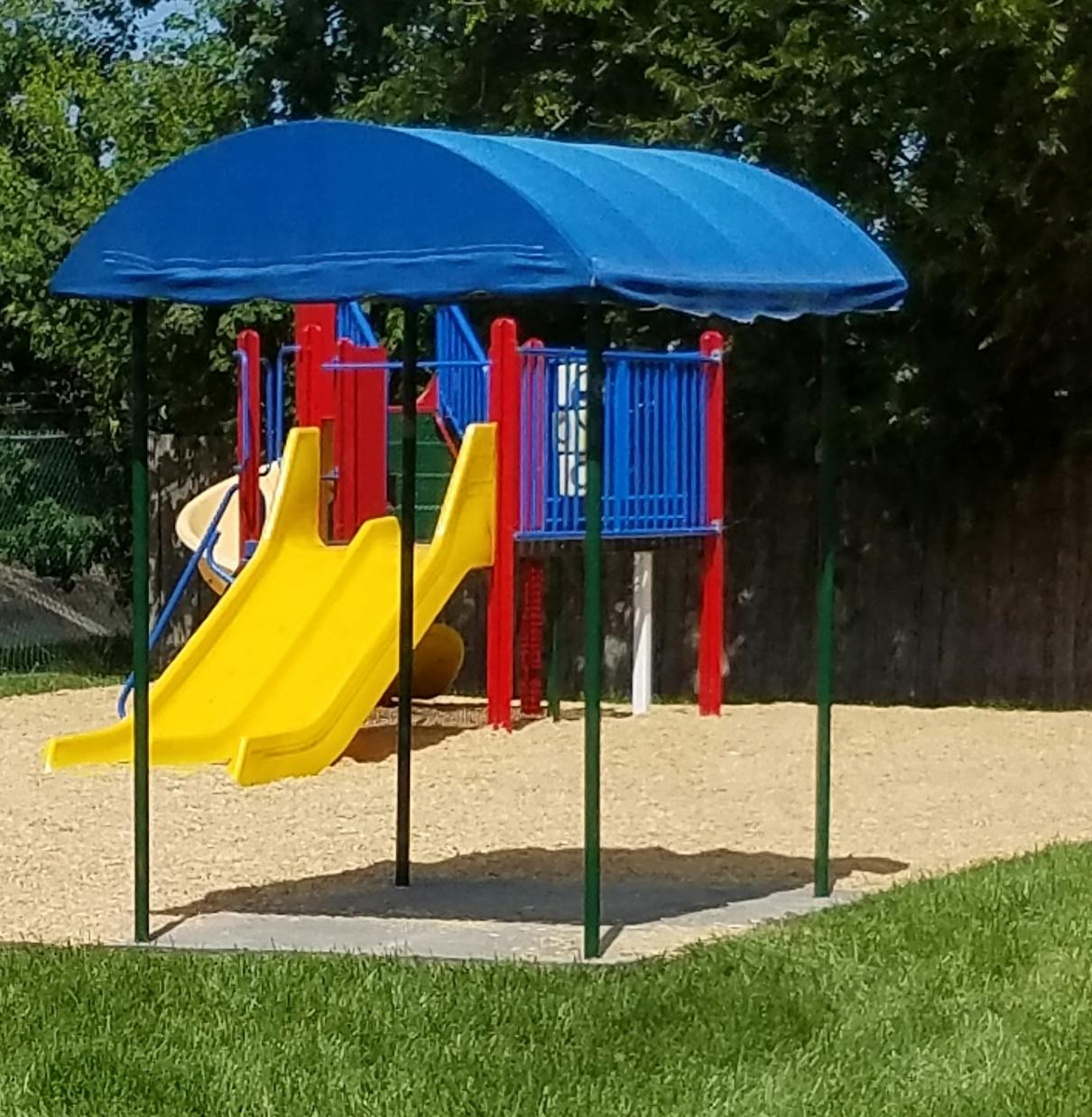 Playground with yellow slides and blue shade canopy