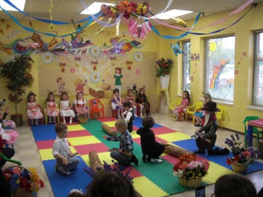 Children sitting on a colorful mat in a decorated room