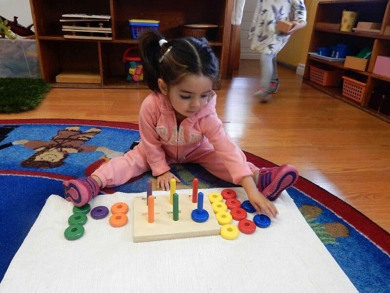 Child playing with a colorful ring stacking toy on the floor