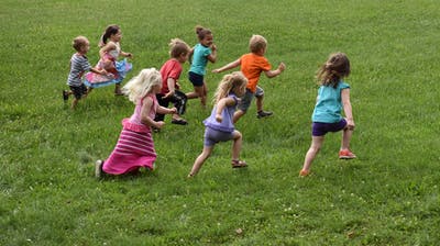 Group of children running across a grassy field