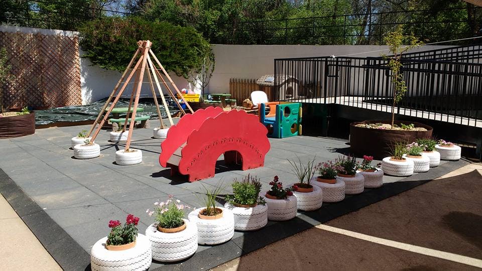Outdoor play area with red arch, wooden structure, and planters