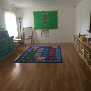 Empty classroom with a blue rug and green bulletin board