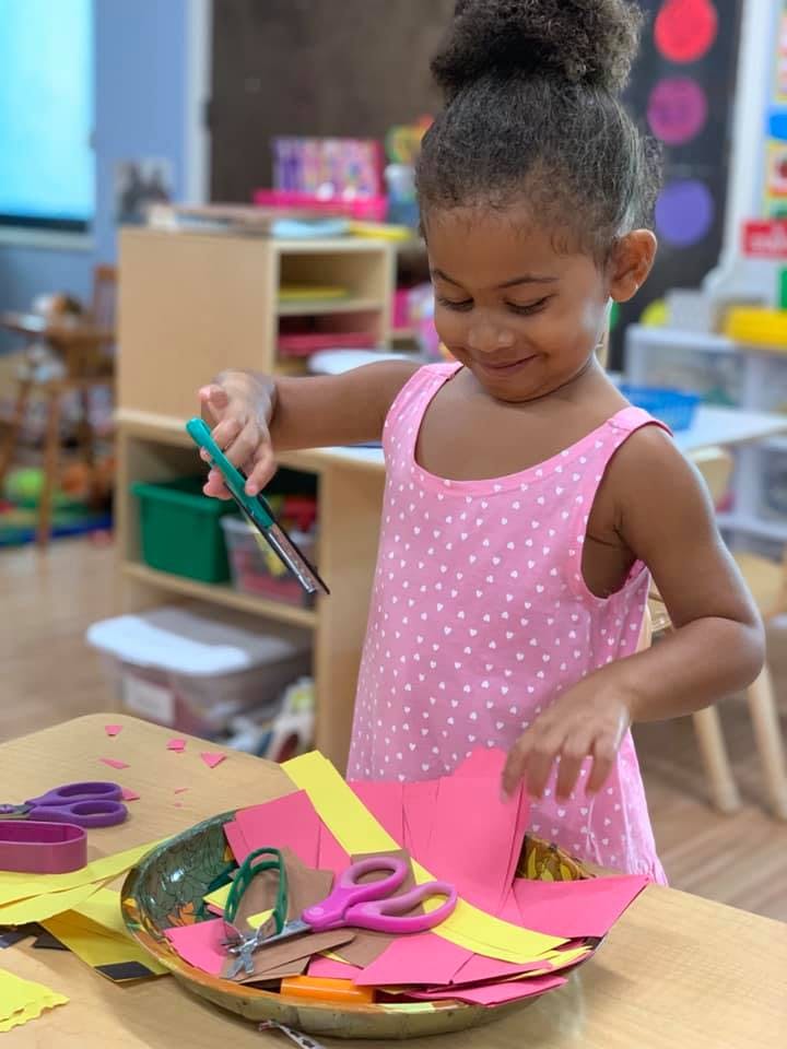 Child cutting paper with scissors in a classroom