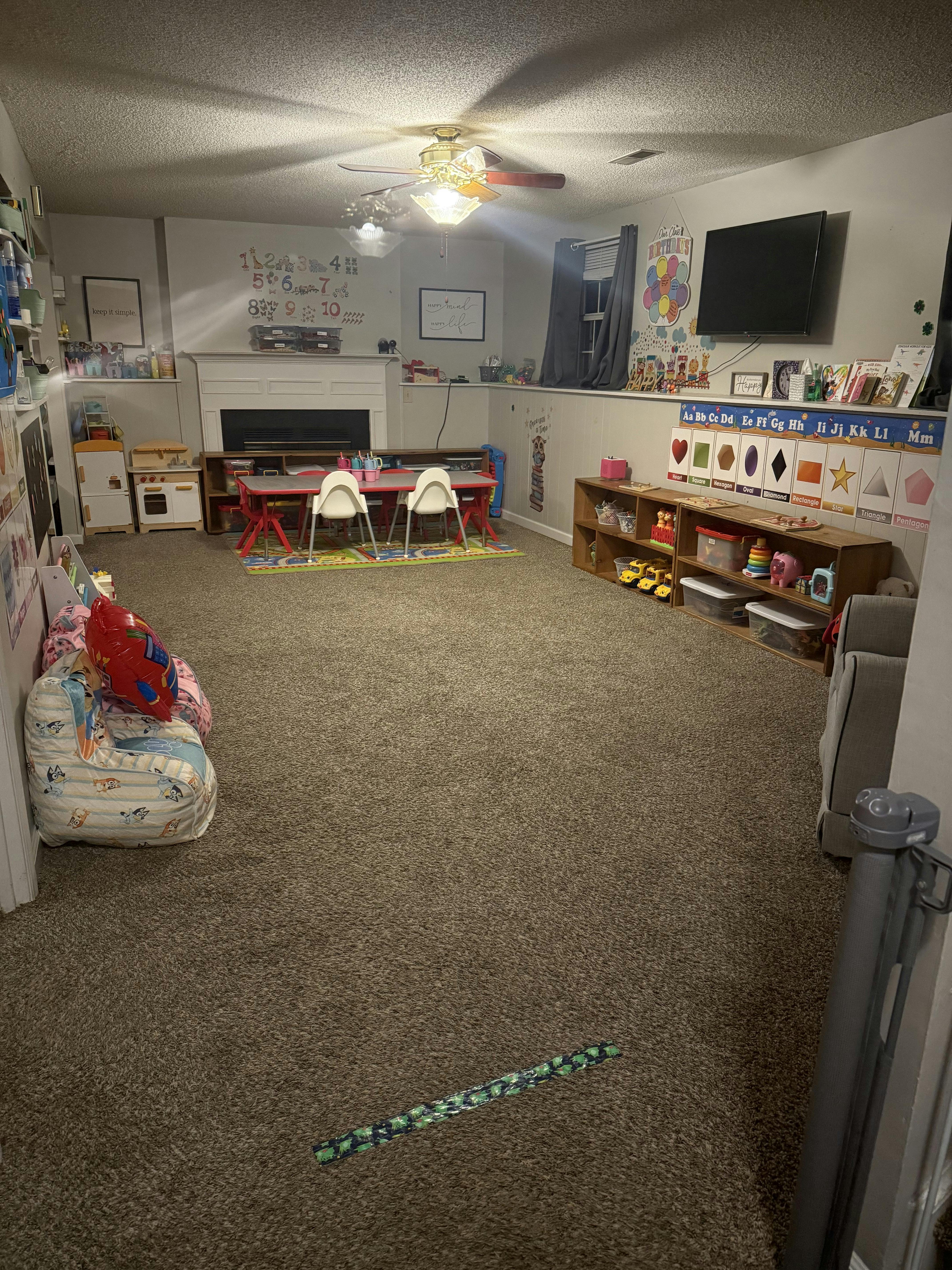 Playroom with a small red table and chairs, shelves with toys, and a TV
