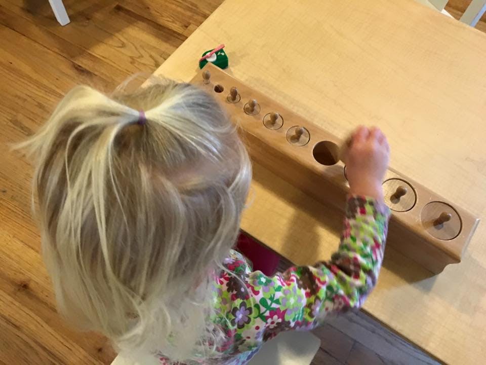 Child playing with a wooden cylinder block puzzle